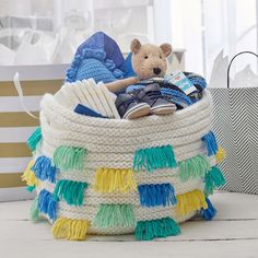 a teddy bear sitting in a basket filled with books and other items on a table