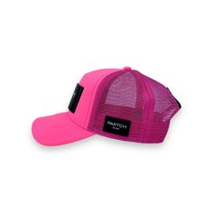 a pink trucker hat with black patch on the front