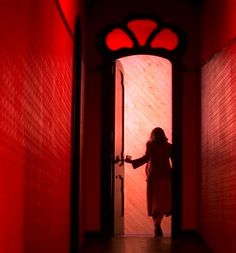 a woman is standing in an open doorway with her hand on the door knobs