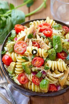 a bowl filled with pasta salad on top of a wooden table