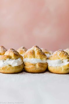 small pastries with cream on them lined up in a row against a pink background