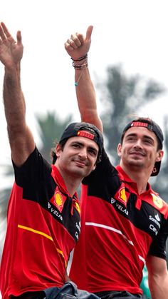 two men in red and black shirts holding up their hands