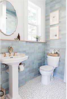 a white toilet sitting next to a sink in a bathroom under a large round mirror