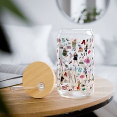 a glass with stickers on it sitting on a table next to a wooden paddle