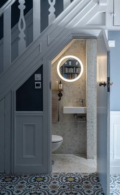 an open door leading to a bathroom with a sink and toilet under a stair case