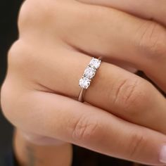 a woman's hand holding a three stone ring