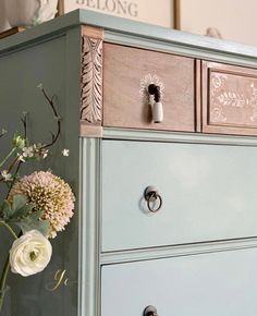 a vase with flowers sitting on top of a blue dresser