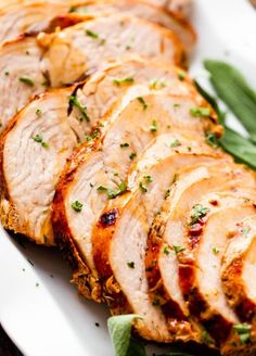 sliced pork on a white plate with green beans and garnished with parsley