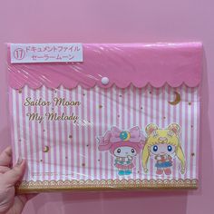 a person holding up a pink and white paper bag with two cartoon characters on it