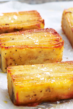 four pieces of cooked pineapple sitting on top of wax paper