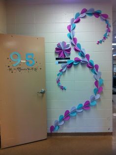 an office door decorated with pink and blue paper streamers in the shape of a heart