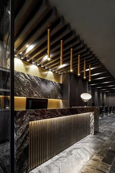 the interior of a modern bar with marble counter tops and gold accents on the walls