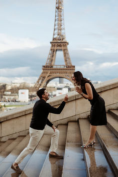 a man and woman standing on the steps in front of the eiffel tower