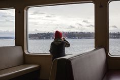 a person wearing a red hat looking out the window on a boat in the water