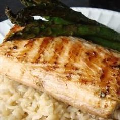 a white plate topped with meat and rice covered in asparagus next to broccoli