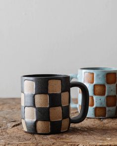 two coffee mugs sitting next to each other on top of a wooden countertop