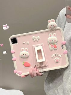 a woman holding up a pink phone case with bunny and rabbit decorations on the back