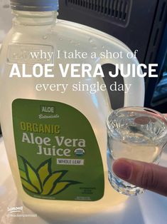 a bottle of aloe vera juice next to a glass with an ice cube in it