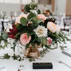 an arrangement of flowers and greenery on a table