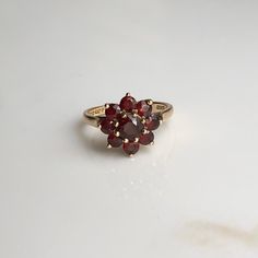 A Vintage 9 carat gold Garnet cluster ring. This beautiful piece holds a gorgeous collection of deep red stones in a gold setting, holding them high up on display. CONDITION: Wear consistent with age and use. Please see photos for more detail. HALLMARKED 9 CARAT GOLD, ASSAYED PRE 1975 STONE SIZE: 5mm (.50 carat) 3mm (.10 carat) SETTING DIAMETER: 12mm SETTING HEIGHT: 7mm BAND WIDTH: 1.5mm RING SIZE: UK: M | US: 6 1/4 WEIGHT: 3.0 grams (UZZ) Serpent Ring, Diamond Signet Ring, Red Stones, Garnet Gem, Citrine Ring, Red Band, Gold Snake, Red Stone, Multi Stone Ring