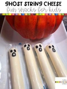 four white plastic utensils sitting on top of a table next to a pumpkin