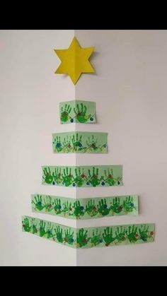 a christmas tree made out of green paper with handprints on it and a star