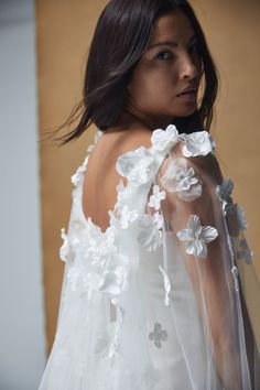 the back of a woman's wedding dress with white flowers and petals on it