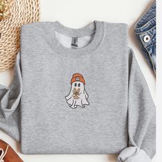 Get ready to embrace the cozy vibes of the fall season with our adorable "Cute Ghost with Dog" Crewneck Sweatshirt. Perfect for dog lovers and fans of cute, spooky designs, this sweatshirt is a must-have addition to your autumn wardrobe. Product Details: Material: Crafted from a comfortable and durable 50/50 cotton polyester blend, ensuring a soft feel and long-lasting wear. Sizes Available: S, M, L, XL, 2XL - fits true to size. Colors Available: Ash, Sport Grey, Dark Chocolate, Forest Green, Graphite Heather, Maroon, Military Green, Sand, Sport Grey, White. Design: Features a charming embroidered design of a cute ghost holding a dog, perfectly centered on the chest. This stylish design is ideal for the fall season, bringing a touch of whimsy and warmth to your outfit. Care Instructions: M Gray Letter Embroidery Sweatshirt For Fall, Casual Letter Embroidery Sweater For Fall, Gray Embroidered Logo Sweatshirt For Fall, Cozy Fall Sweatshirt With Letter Embroidery, Cozy Sweatshirt With Letter Embroidery For Fall, Fall Crew Neck Sweater With Letter Embroidery, Casual Fall Sweatshirt With Letter Embroidery, Cozy Letter Embroidery Sweatshirt For Fall, Gray Embroidered Logo Top For Fall