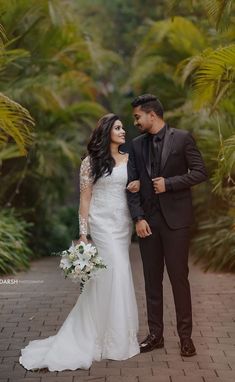 a bride and groom standing in front of palm trees