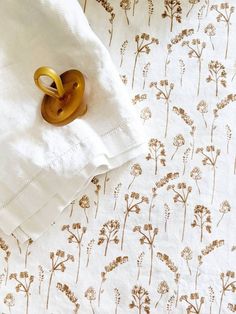 two gold rings sitting on top of a white sheet with brown flower designs in it