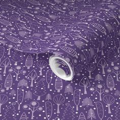 a purple wallpaper with white trees and dots on the surface, as well as a roll of tape