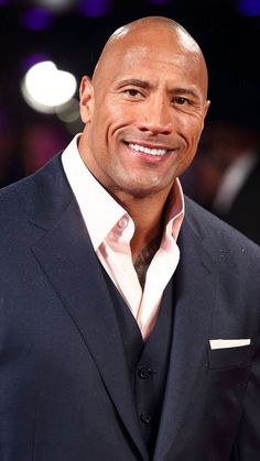 the rock is smiling and wearing a suit