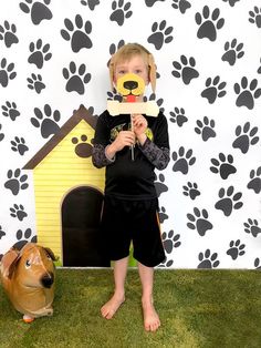 a little boy standing in front of a dog house with a paper mask on his face