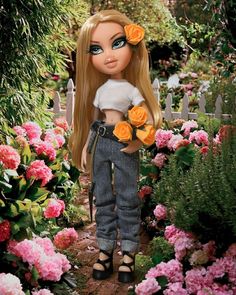 a doll with long blonde hair and flowers in her hand is standing among the roses