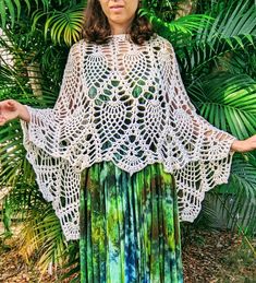 a woman standing in front of some plants wearing a crochet top and skirt