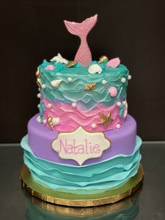 there is a colorful cake with a mermaid tail on it and the name nalaie