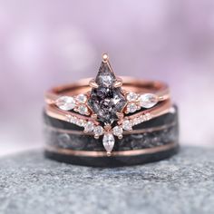 two wedding rings with diamonds on top of each other, sitting on a rock in front of a blurry background