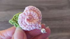 a crocheted flower is being held in someone's hand with a bead earring