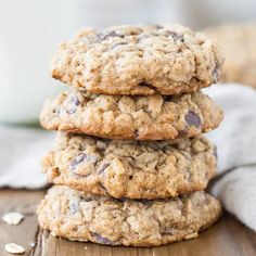 three oatmeal cookies stacked on top of each other with a glass of milk in the background