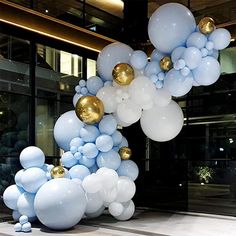 blue and white balloons are hanging from the ceiling