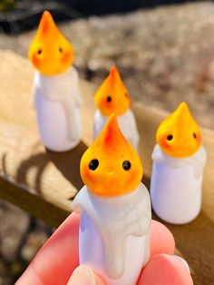 small orange and white figurines sitting on top of a wooden bench in front of someone's hand