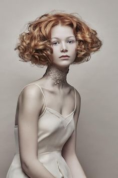 a woman with red hair and tattoos on her neck is posing for a photo in white dress