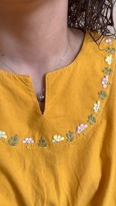 a close up of a person wearing a yellow shirt with flowers on the front and side