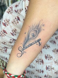 a woman's arm with a feather on it and a pipe in the middle