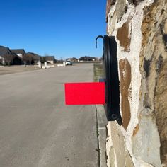 a red and black sign on the side of a stone wall next to a street