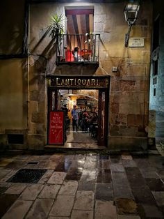 an entrance to a restaurant at night with people walking in the doorway and onlookers