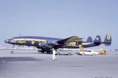 a blue and yellow airplane is on the tarmac at an airport with other vehicles around it