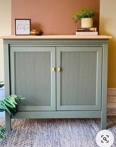 a green cabinet sitting on top of a rug next to a potted plant