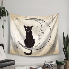 a black cat sitting on top of a crescent moon next to a potted plant