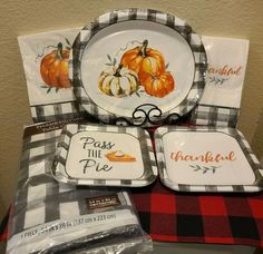 a table topped with plates and napkins covered in thanksgiving themed designs, including pumpkins